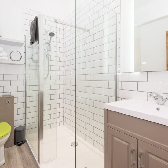 Weiß geliestes Badezimmer mit Möbeln in Taupe und Toilettensitz in grün.