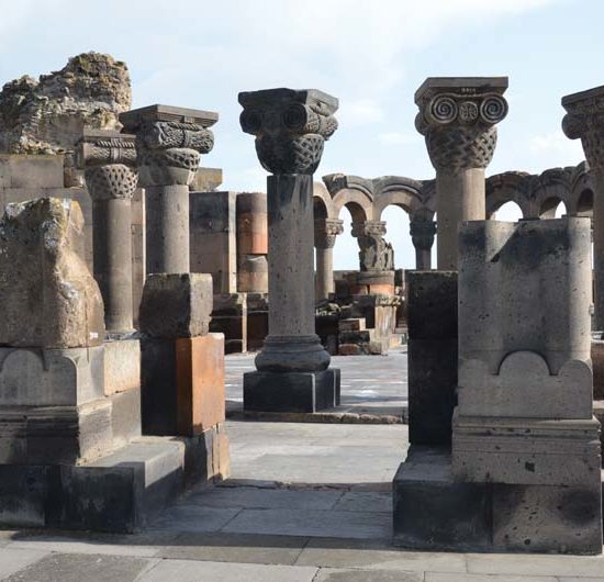Ruinenanlage des Zentralbaus von Zvarnots mit von ionischen Kapitellen bekrönten Säulen und Bögen im Hintergrund.
