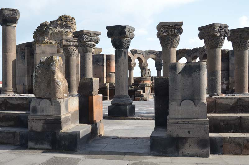 Ruinenanlage des Zentralbaus von Zvarnots mit von ionischen Kapitellen bekrönten Säulen und Bögen im Hintergrund.
