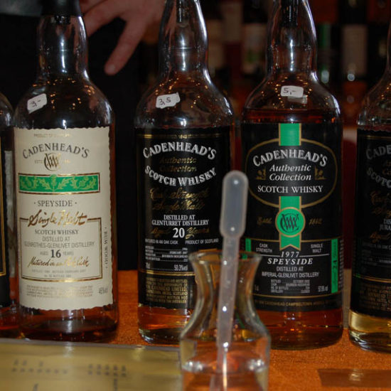 Fünf Whiskyflaschen von Cadenhead mit einem kleinen Wasserkrug und Pipette.