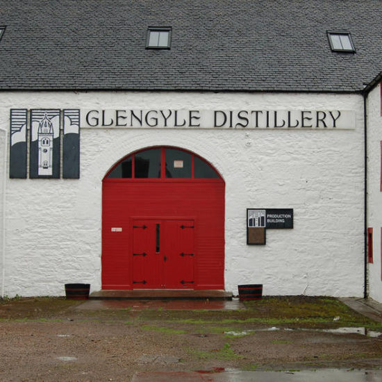 Weißes Gebäude der Glengyle Distillery mit großem roten Tor.