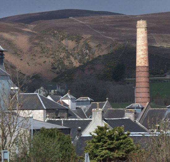 Schiefergedeckte Dachlandschaft und der Backsteinturm der Brora Distillery in den nördlichen Highlands.