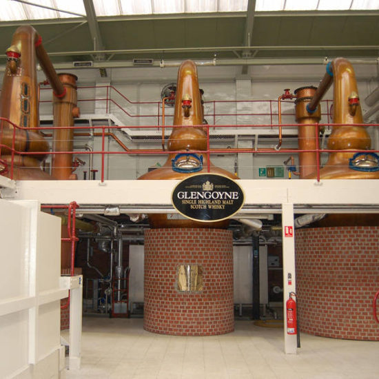 Stillroom von Glengoyne mit drei Kupferbrennblasen die auf einem Backsteinsockel stehen.