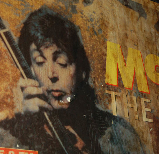 Altes vergilbtes Plakat auf dem Paul McCartney Gitarre spielt.