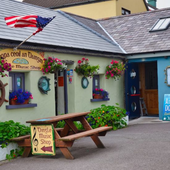 Kleine bunte Häuser eines Musik Shops und eines Restaurants mit irischen Beschriftungen, amerikanischer Flagge und Tisch.