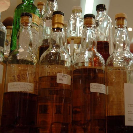 Blick von schräg unten auf Whiskyflaschen mit handgeschriebenen Etiketten.