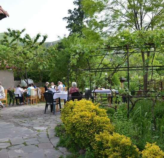 Gartenrestaurant, an den Tischen sitzen einige Menschen.