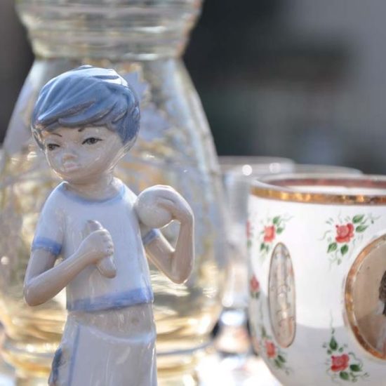 Hellblaue Porzellanfigur eines Jungen und Tasse mit Portrait einer Frau.