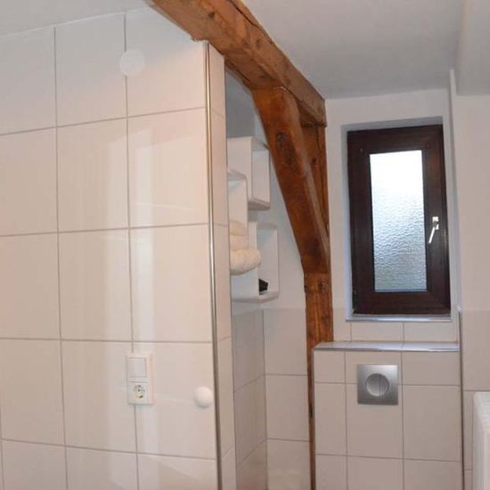 Hell gefliestes Badezimmer mit Holzbalken und Fenster.