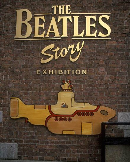 Dunkelrote Backsteinwand mit goldenem Werbeschriftzug The Beatles Story Exhibition und darunter einem gelb-goldenen U-Boot.