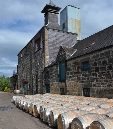 Schiefergedeckte Steingebäude mit Pagode und neuen Whiskyfässern, die im Hof der BenRiach Destillerie liegen.
