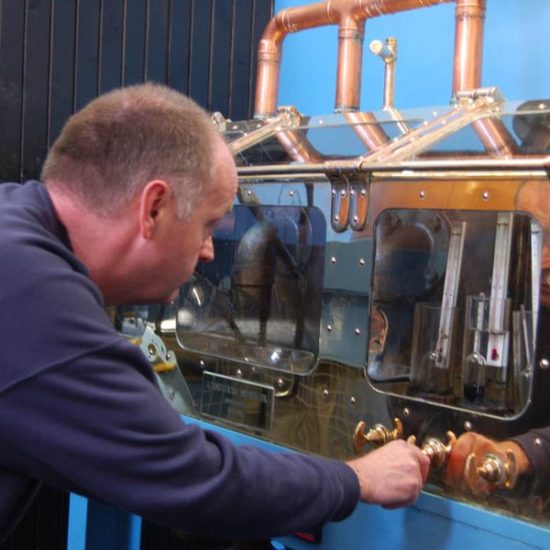 Ein Mann prüft und reguliert die Messungen im kupfernen Spirit Safe der Glen Moray Distillery.