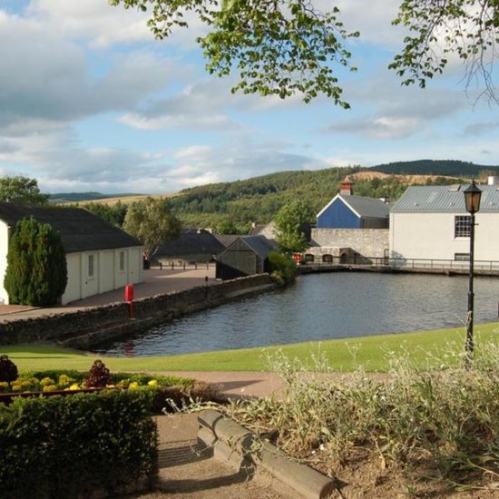 Teich der Glenfiddich Distillery, umrahmt von Gebäuden der Whiskybrennerei.