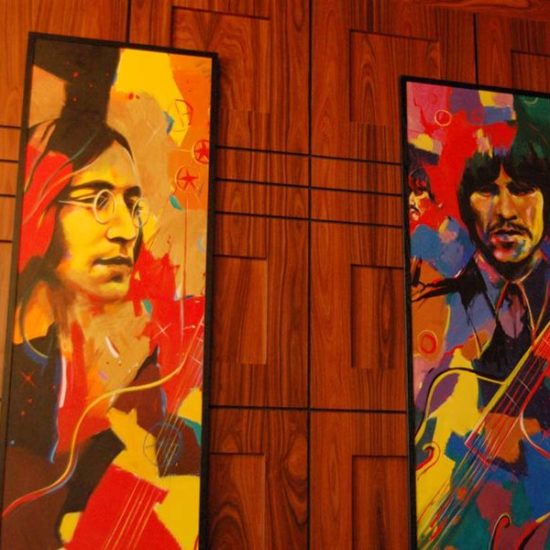Holzwand mit sehr bunten, abstrakten Bildern der Beatles.