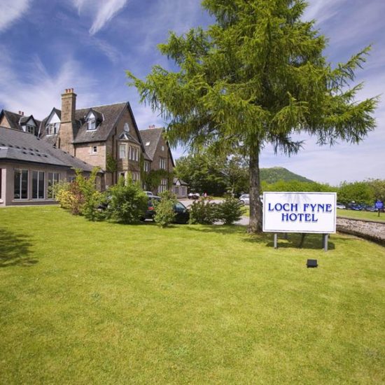 Sonnige Aufnahme des Loch Fyne Hotels mit Baum und Firmenschild.