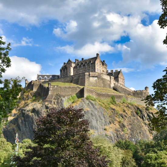 Edinburgh Castle erhebt sich bei gutem Wetter auf einem hohen Felsen.