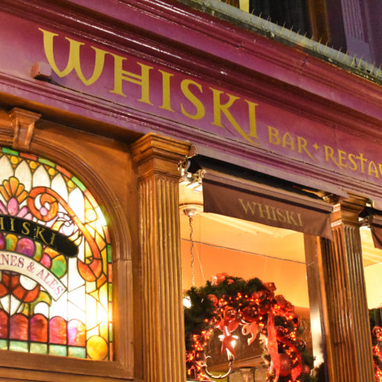 Schriftzug Whiski an einem Bar Restaurant, dessen rote Fassade weihnachtlich geschmückt ist.