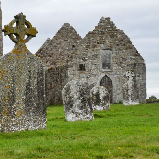 Bruchsteinbauten der Klosterruine von Clonmacnoise mit Grabsteinen und keltischen Hochkreuzen.