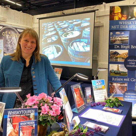 Die Reiseveranstalterin Birgit Bornemeier präsentiert Broschüren und Whiskykarten am Stand von REISEKULTOUREN.