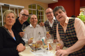 Vier Männer und eine Frau halten Whiskygläser und lachen in die Kamera.