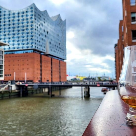 Glas der Whisky Live Germany-Messe vor dem Hintergrund der Elbphilharmonie.